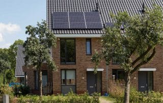 Bakstenen nul op de meter rijtjeswoning hoekhuis met schuin dak met donkere dakpannen en zonnepanelen in Apeldoorn